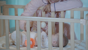 4k升格宝宝在婴儿床里和妈妈互动玩玩具特写7秒视频