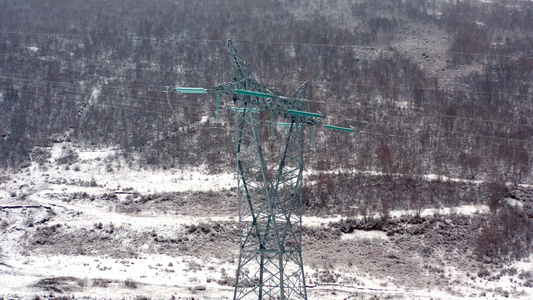 4K航拍雪景下雪天气的电力输送铁塔视频