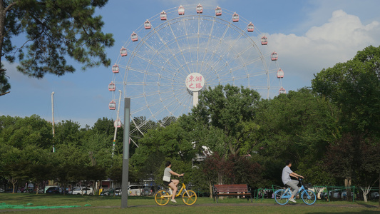 城市蓝天白云晴朗天空摩天轮下休闲娱乐的行人街景4k素材视频