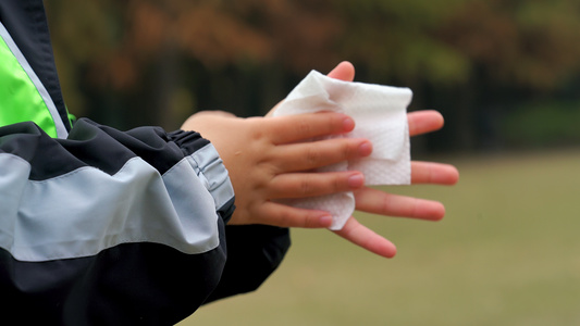 4K秋冬公园小男孩手部消毒完使用纸巾擦拭特写视频