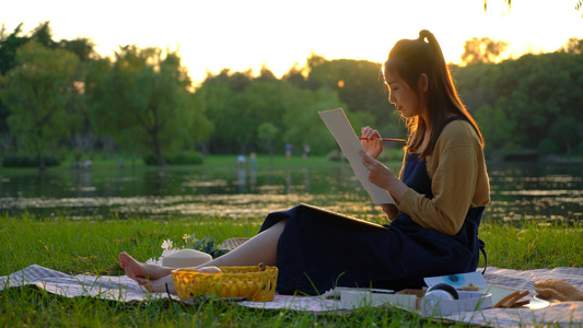 夕阳下河边画画的女青年视频