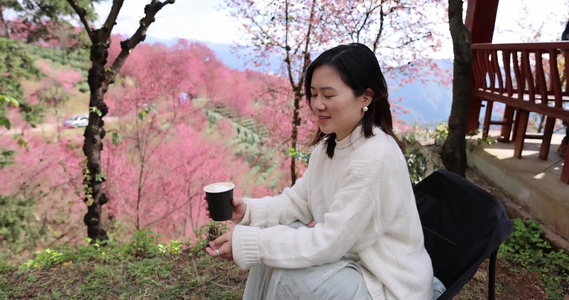 在樱花树下喝咖啡的年轻美女唯美慢镜头视频
