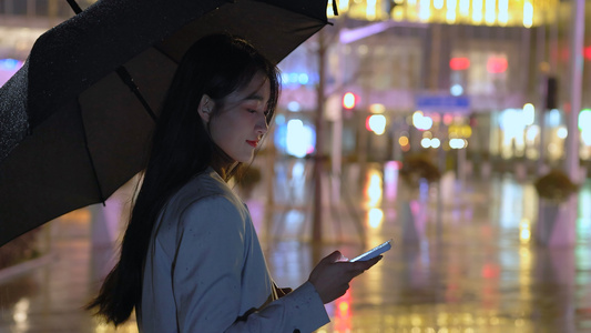 夜晚女人撑伞在路边用手机视频