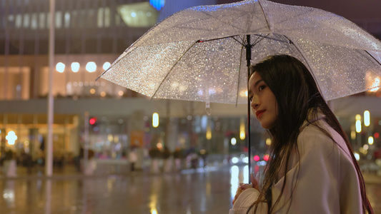 夜晚女人撑伞在路口等车视频