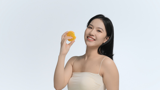 女人拿着香橙展示面容视频