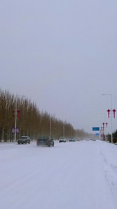 实拍北方飘雪的冬季街道上缓慢行驶的汽车视频