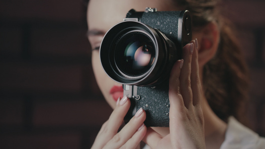 在砖墙背景上用旧摄影机拍照的漂亮女人视频