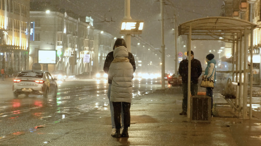 大雪纷飞的夜晚等待公交车的情侣视频