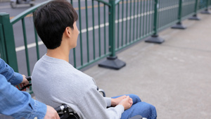 亲人陪伴坐轮椅的青年男性外出16秒视频