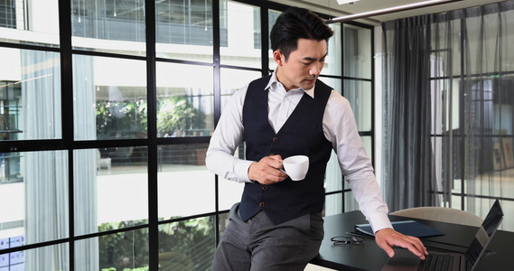 一个商务男士靠在会议桌前办公喝咖啡视频