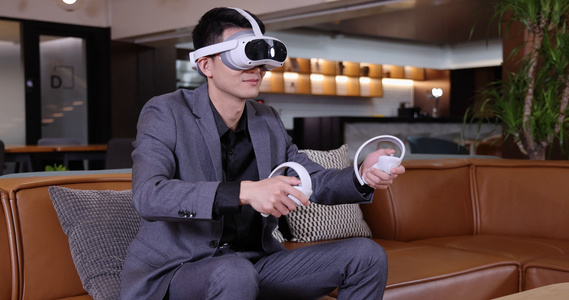 商务人士坐在沙发上玩VR游戏机视频