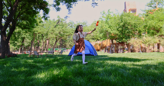 小女孩在草地上举着风车开心奔跑视频