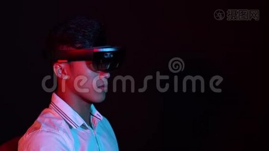 商人在黑暗的房间里试着戴上VR眼镜。 年轻亚洲男孩经历AR交流的肖像。 未来视频