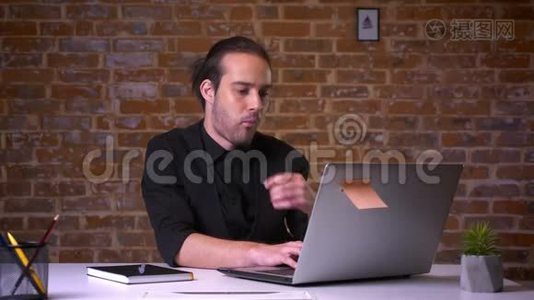 漂亮的白种人上班族在电脑前思考和咬手，电脑后面有砖墙视频