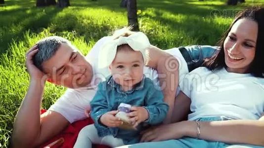 可爱的女婴抱着鞋子，父母躺在公园的草地上视频