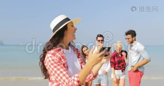 在沙滩上拍照的女孩手机上拍照的人快乐的男人和女人度假的游客视频