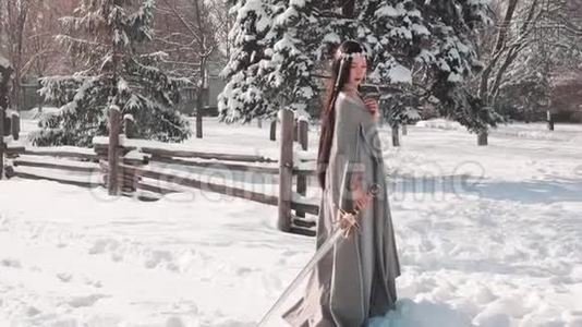迷人的黑发女子独自站在她的村庄出口，把她的剑在雪中，看上去悲伤，好战的视频