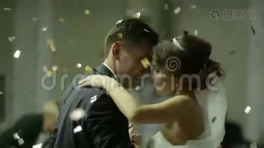 美丽的黑发新娘和英俊的新郎在婚礼上跳舞。 空中的纸屑.. 非常招标视频