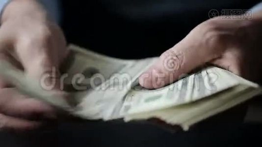一个商人的手在桌子上数着一百美元的钞票视频
