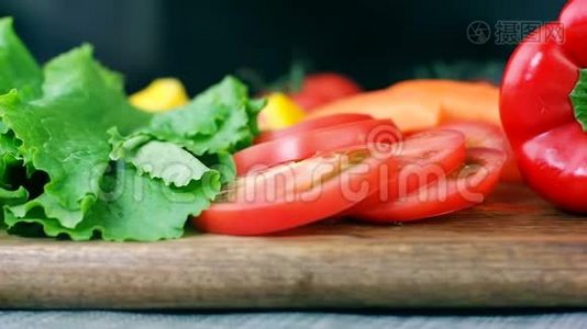 沙拉叶，切好的番茄，胡椒和胡萝卜放在木板上，做健康的蔬菜沙拉，小圆片视频