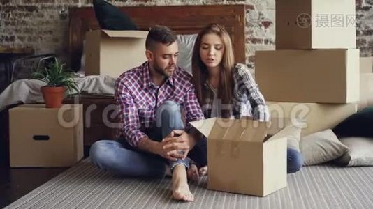 幸福的一对夫妇在搬迁后打开盒子，一起看照片，谈笑风生视频