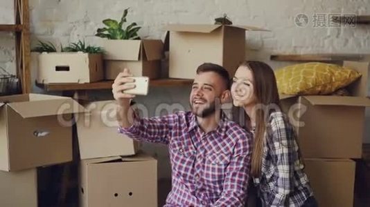 幸福的年轻夫妇在搬迁后用智能手机打视频电话。 他们在问候朋友，展示新房子视频
