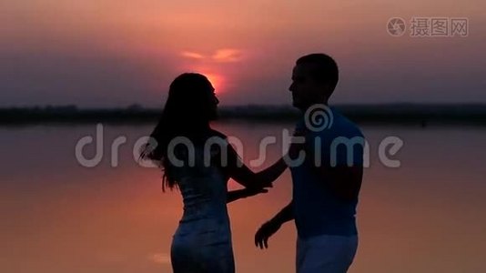 剪影男人和女人在日落时跳舞。 慢慢视频