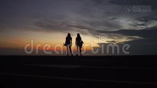 女朋友在山顶上玩滑板后看日落的美丽景色视频