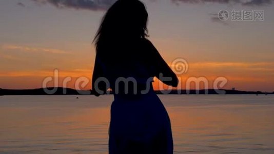 日落时分，幸福的女人来到海滩，举起双臂，转身视频