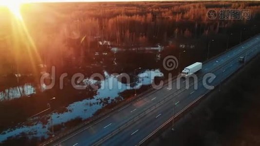 一辆半卡车在高速公路上行驶，进入日落，前视空中摄像机。视频