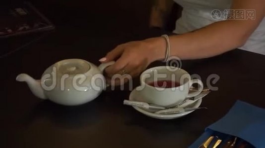 茶被倒入玻璃透明茶杯中。 一杯茶。 糖果，热茶和茶壶.. 陶瓷茶壶和玻璃茶杯特写..视频