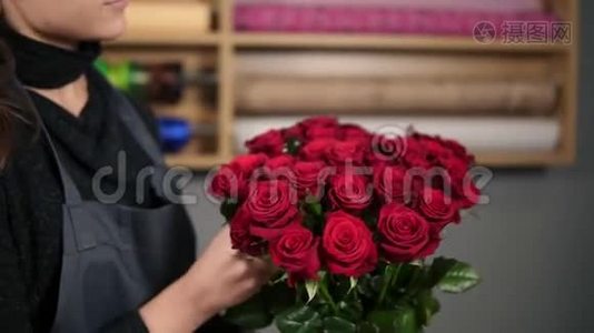 关注一束红玫瑰：年轻迷人的女性花店在花店里布置一束美丽的红玫瑰视频