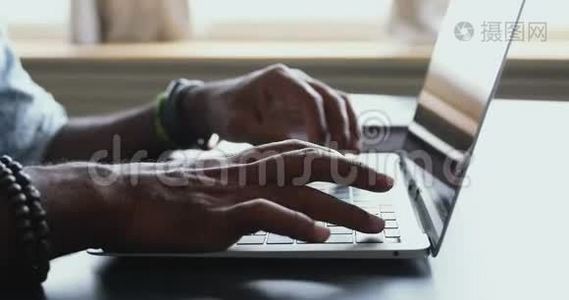 美国黑人男性用户在桌旁的笔记本电脑上打字，特写视频