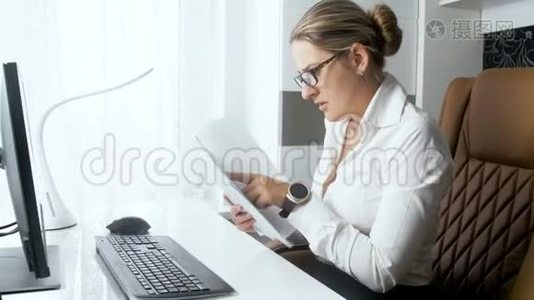 年轻优雅的女商人在办公室用台式电脑阅读文件的4k镜头视频