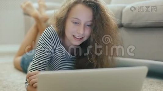 沙发上的少女正在从笔记本电脑上看书，微笑着看着相机视频
