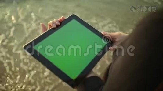 女人在海边的绿色屏幕上使用平板电脑视频