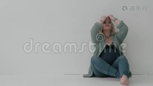 大龄孕妇坐在白色的墙上。 关于分娩的梦。视频