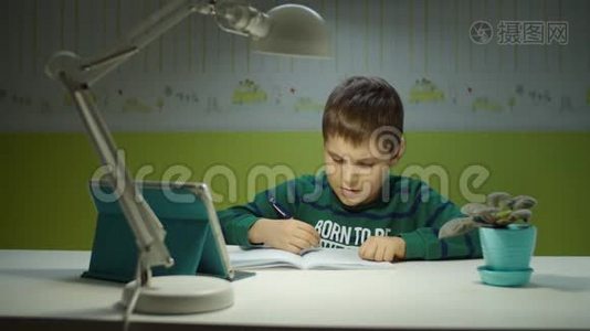 小学生用平板电脑做在线作业。 孩子坐在书桌前，在儿童室上网学习视频