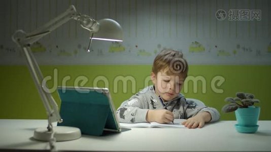 用平板电脑做在线作业的学龄前男孩。坐在书桌边和孩子们一起在线学习的孩子视频