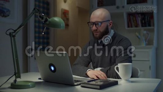 30多岁的男教师戴着眼镜，通过视频电话和学生打招呼，并在感情上做手势，看着笔记本电脑。视频
