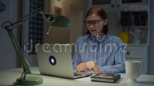 30多岁的年轻女教师戴着眼镜说话和做手势，情绪激动地看着家里的笔记本电脑。 在线教育视频
