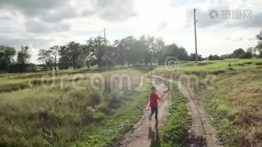 一个小男孩带着风筝跑过田野。 孩子在大自然中散步视频