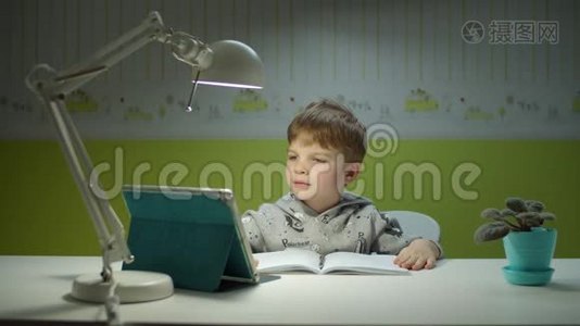 用平板电脑做在线作业的学龄前男孩。坐在书桌边和孩子们一起在线学习的孩子视频