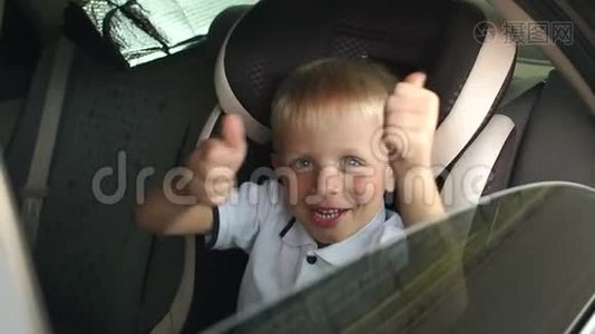一个快乐的小男孩坐在棕色的儿童汽车座椅上，竖起大拇指。视频