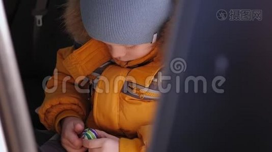 一个悲伤的男孩坐在一个孩子的座`冬天，带着一个小球的肖像视频