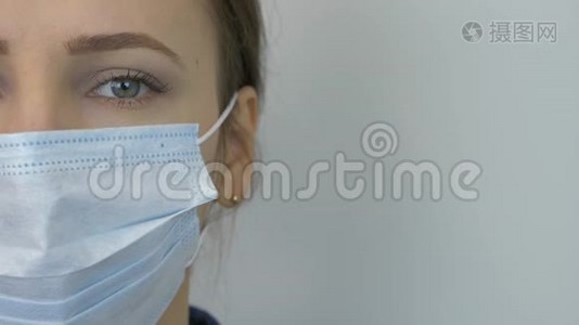 对Covid-19冠状病毒的大流行保护。 戴防护医用面罩的年轻女性肖像。 白人女性穿着视频