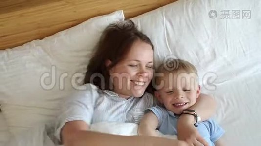 早上妈妈和小儿子在床上的肖像，他们醒来拥抱。视频