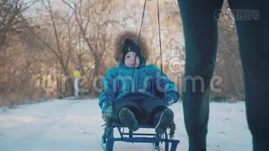 父母在冬天带着快乐的小男孩在雪橇上。 幼儿玩雪橇。 家庭圣诞节的户外乐趣视频