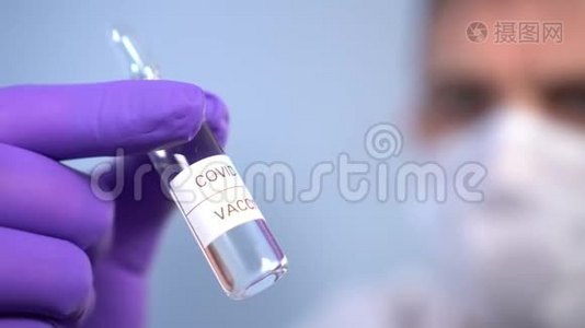 冠状病毒疫苗安瓿在医生手中`面罩和防护医疗手套在蓝色背景视频