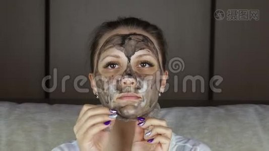美丽的女人从脸上摘下清洁的黑色面具视频